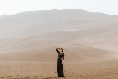女人站在棕色的金沙
